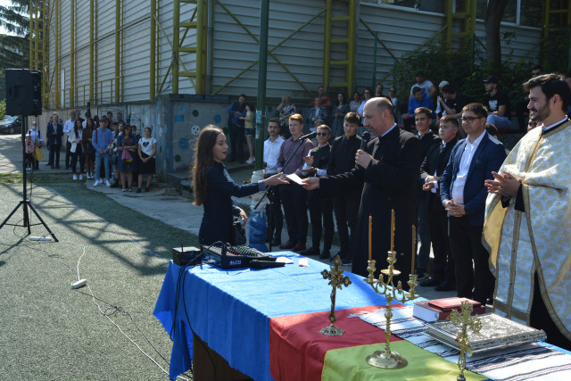 Părintele Partenie Apostoaie oferind Bursa IPS Teofan de 1000 de lei elevei Cozma Maria